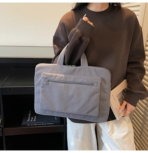 Detailed view of grey corduroy laptop bag texture and spacious front zipper pocket