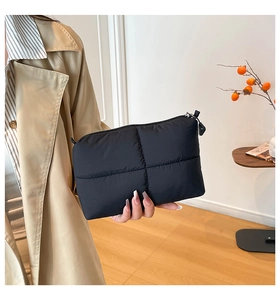 Close-up of quilted black puffy makeup bag held by a model in an aesthetic room