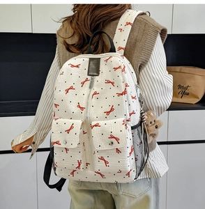 Détail du sac à dos blanc élégant avec nœuds rouges et porte-clés ourson en peluche brun