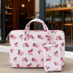 Pink butterfly print laptop bag and small organizer pouch set on a wooden surface