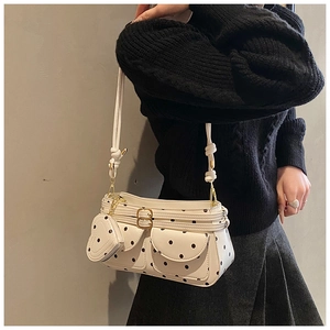 Polka-Dot Schultertasche mit Herzanhänger am Modell mit schwarzem Pullover und Rock