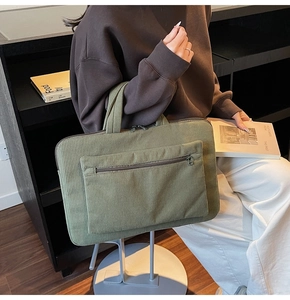 Detail of dark green corduroy laptop bag showing striped texture and zip pocket