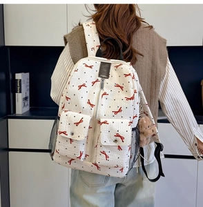 Gros plan du sac à dos blanc texturé avec nœuds rouges, pois et porte-clé ours