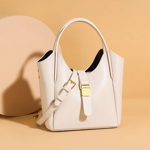 Détails macro du cuir grainé beige et de la quincaillerie dorée du sac à bandoulière