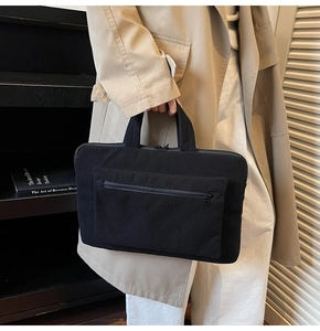 Detail of black corduroy laptop sleeve showing fine ribbed texture and front zipper pocket