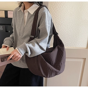 Detalle de gran capacidad y textura de lona a cuadros del bolso hobo marrón en una modelo