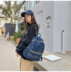 Mannequin portant un grand sac à dos en jean bleu marine avec plusieurs poches zippées en ville