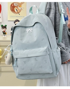 Detail view of mint green backpack with bow prints and side drawstring pocket detail