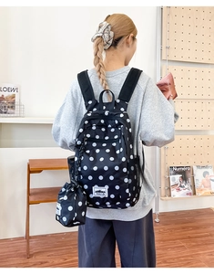 Detailed side view of the black polka dot backpack with mesh side pocket and mini pouch