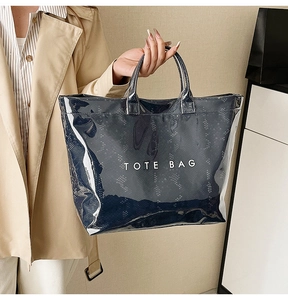 Detail of semi-transparent black tote bag with white TOTE BAG lettering and double handles