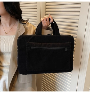 Close-up of a black corduroy laptop bag with a front zipper pocket and dual handles