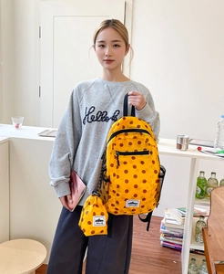 Detailed view of yellow polka dot backpack and matching pouch with brand label
