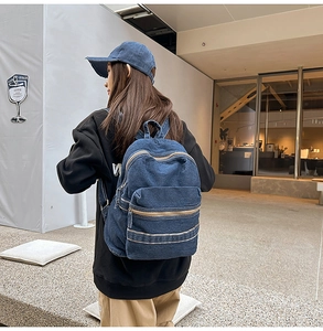 Sac à dos en denim bleu foncé avec poches zippées porté par un mannequin en ville