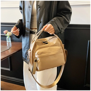 Beige versatile crossbody bag styled with a leather jacket in a modern setting