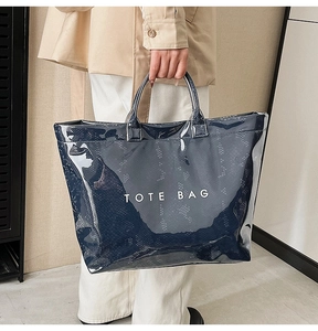 Close-up of shiny navy blue tote bag with white lettering and faux snakeskin texture
