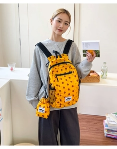 Bright yellow polka dot backpack with matching mini drawstring pouch in a lifestyle setting