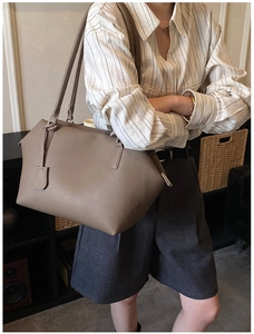 Macro detail of taupe leather tote with grain texture and thin shoulder straps