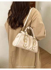 Detail showing creamy beige glossy tote bag with vintage pleated design and gold hardware