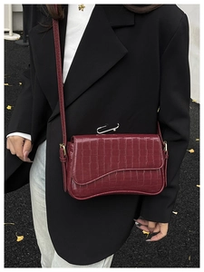 Detail of burgundy crocodile pattern crossbody bag featuring unique silver paperclip hardware