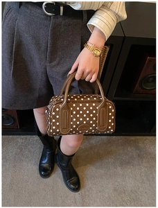Close-up of a brown polka dot Boston bag with double handles and polished faux leather