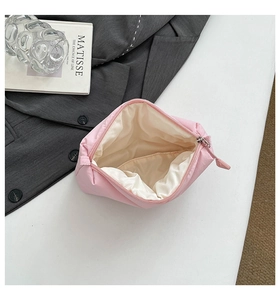 Detailed view of pink quilted cosmetic bag open showing spacious beige interior lining