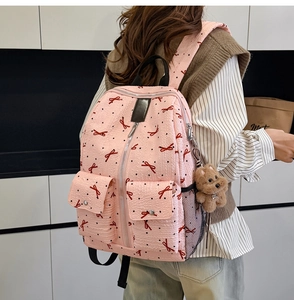 Détail du sac à dos rose à motifs nœuds avec texture gaufrée et breloque ourson