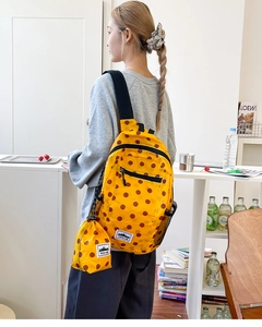 Detail view of yellow polka dot backpack with side mesh pocket and mini matching pouch