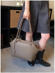 Close-up of taupe grainy calfskin tote bag with leather tag and zipper detail