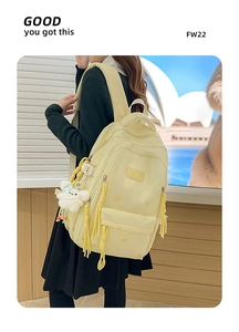 Detailed view of beige backpack with bow embroidery and cute puppy plush pendant charm
