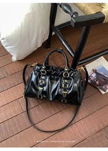 Detail of glossy black pleated leather texture and gold metal hardware on handbag