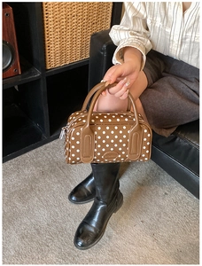 Detailed view of the brown polka dot Boston bag featuring the round brand logo and zip closure