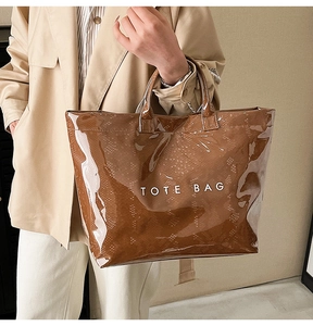 Macro shot of brown glossy tote bag showing snakeskin texture and white logo print