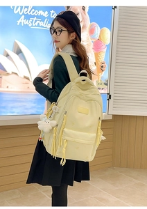 Detail of creamy yellow nylon backpack with butterfly embroidery and plush toy charm