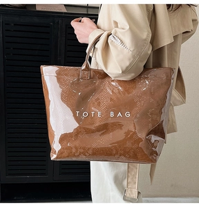 Close-up of brown snake skin texture tote bag with glossy finish and white letter print