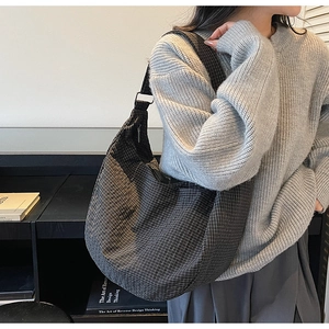 Detalle del bolso hobo a cuadros que muestra la textura en blanco y negro y la correa ajustable