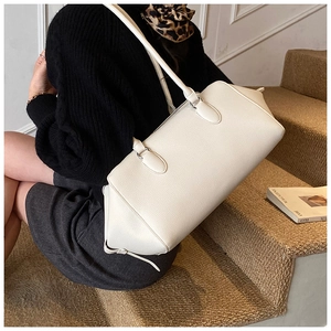 Primo piano di una borsa bowling in pelle bianca con trama litchi indossata da modella