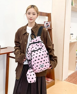 Detailed view of a pink polka dot backpack with a matching mini round coin purse charm