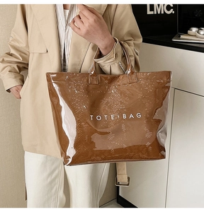 Close-up of brown snakeskin tote bag with shiny PVC coating and white TOTE BAG text