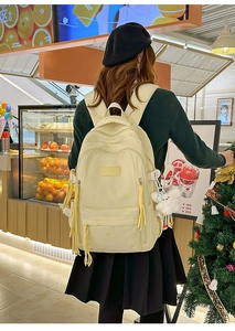 Detail of cream casual backpack with bow embroidery and white plush pendant