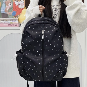 Detail of black backpack with star and music note patterns and vertical zipper pocket