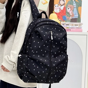 Detail of black nylon backpack with white star pattern and side drawstring pocket