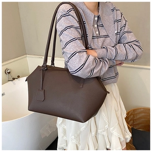 Detailed close-up of dark brown calfskin tote bag featuring minimalist slim shoulder straps