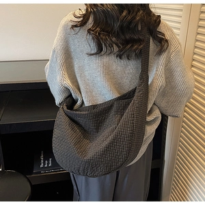 Detalle de bolso tote de cuadros con correa ancha de hombro con un suéter de punto gris