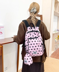 Pink polka dot backpack detail showing side mesh pocket and matching mini round pouch
