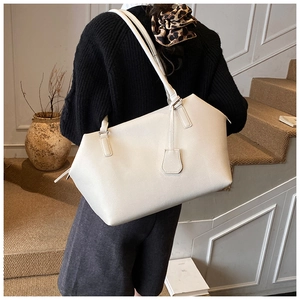 Spacious off-white calfskin tote bag with textured grain shown on a model's shoulder