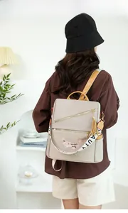 Détail d'un sac à dos beige en tissu Oxford avec broderie florale et pompon