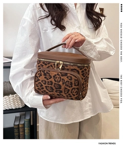 Close-up of leopard print makeup bag with leather handle and golden zipper detail