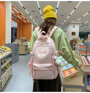 Pink minimalist backpack featuring delicate floral embroidery and a plush lamb pendant