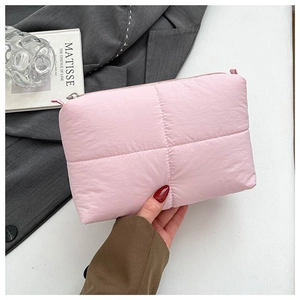 Pink quilted cloud makeup bag with soft puffy texture and matching handle held in hand