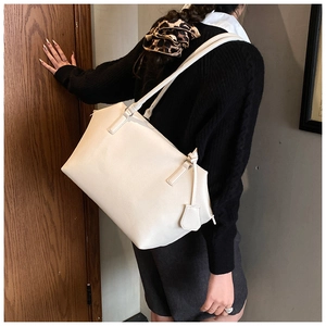 Détail du grand sac cabas en cuir de veau grainé blanc porté à l'épaule par un mannequin